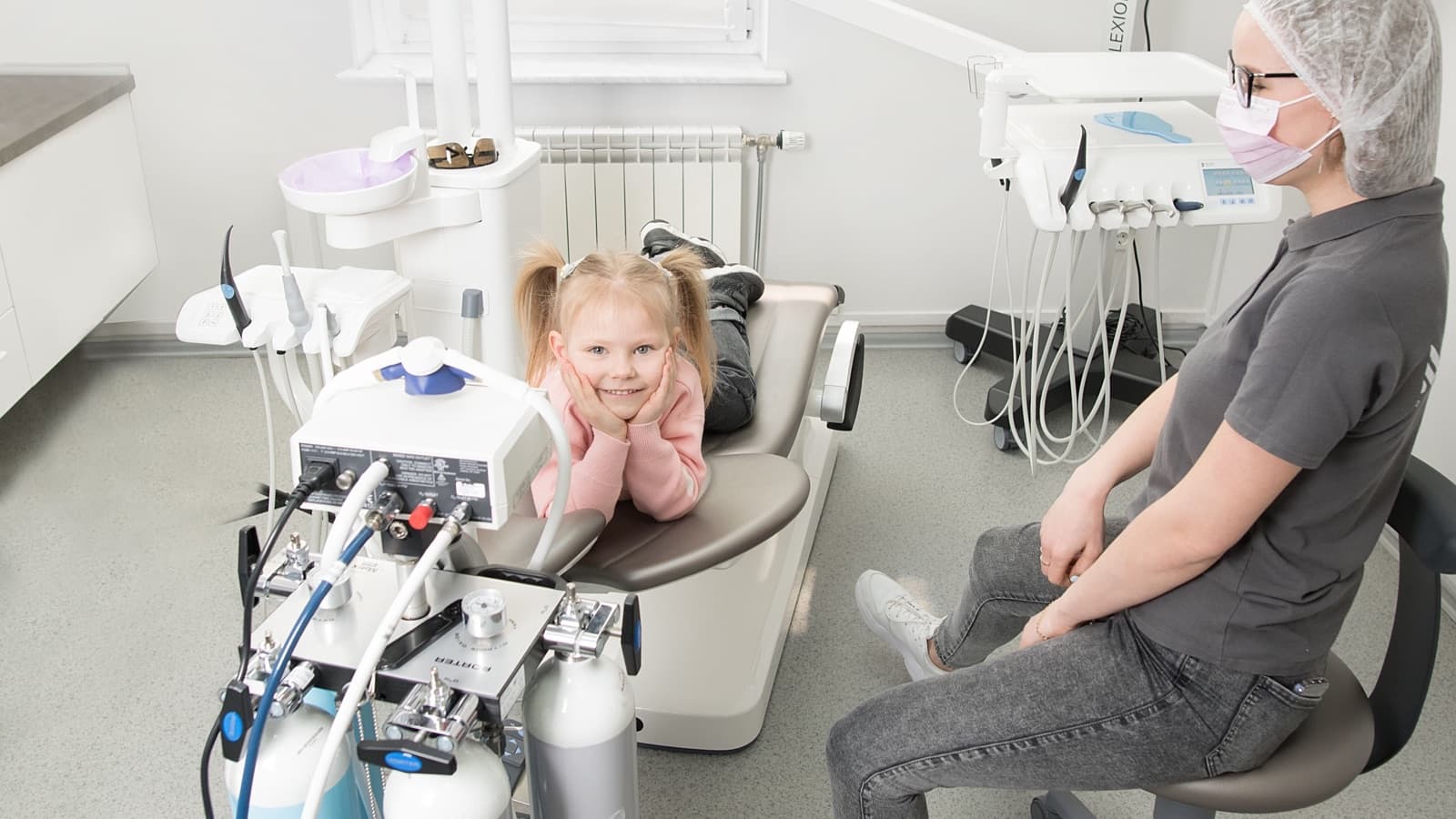 Kind im Behandlungsstuhl mit einer Zahnärztin in einem hellen Behandlungszimmer